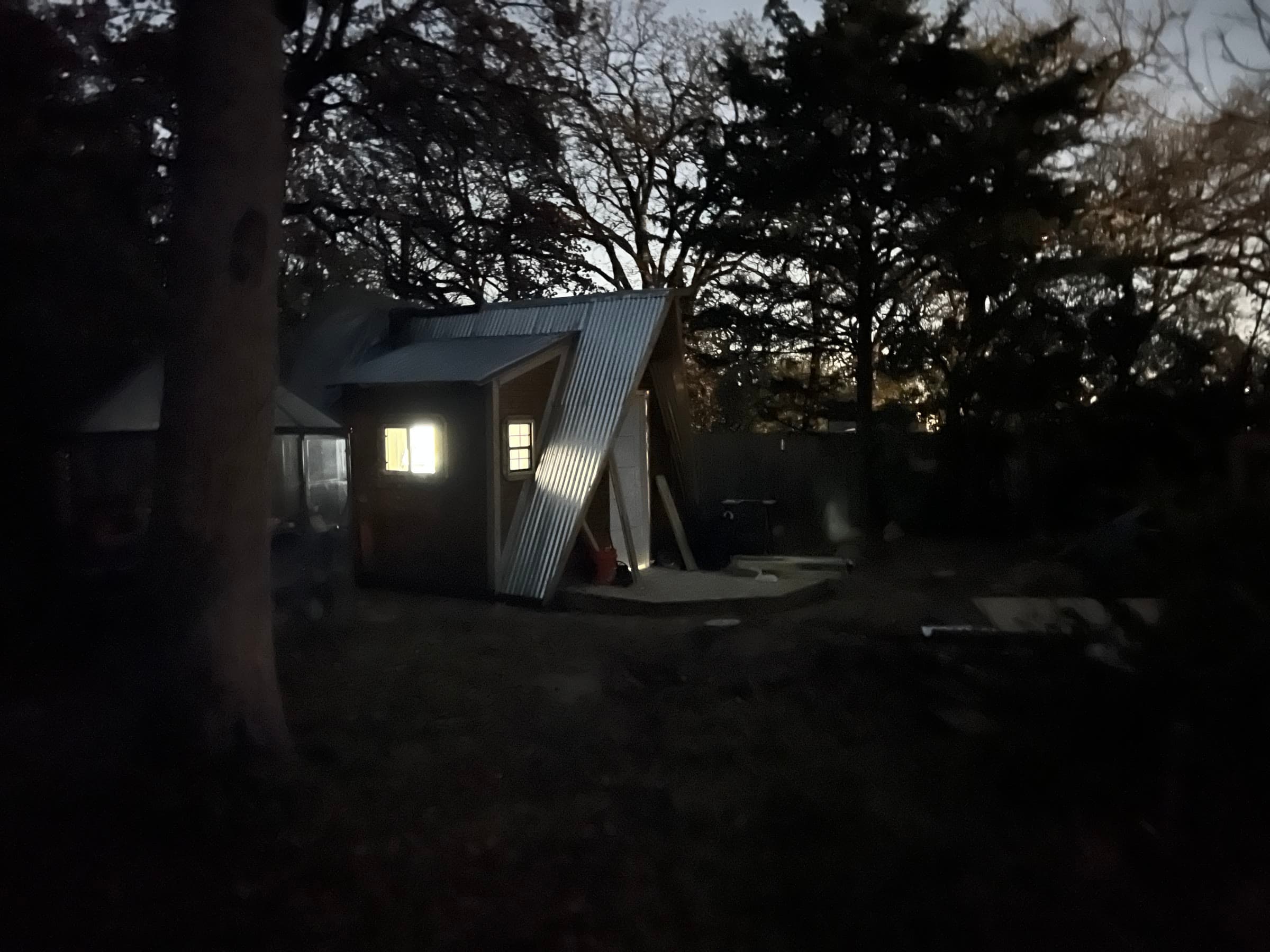 The tiny house at dusk, warm light coming through the window